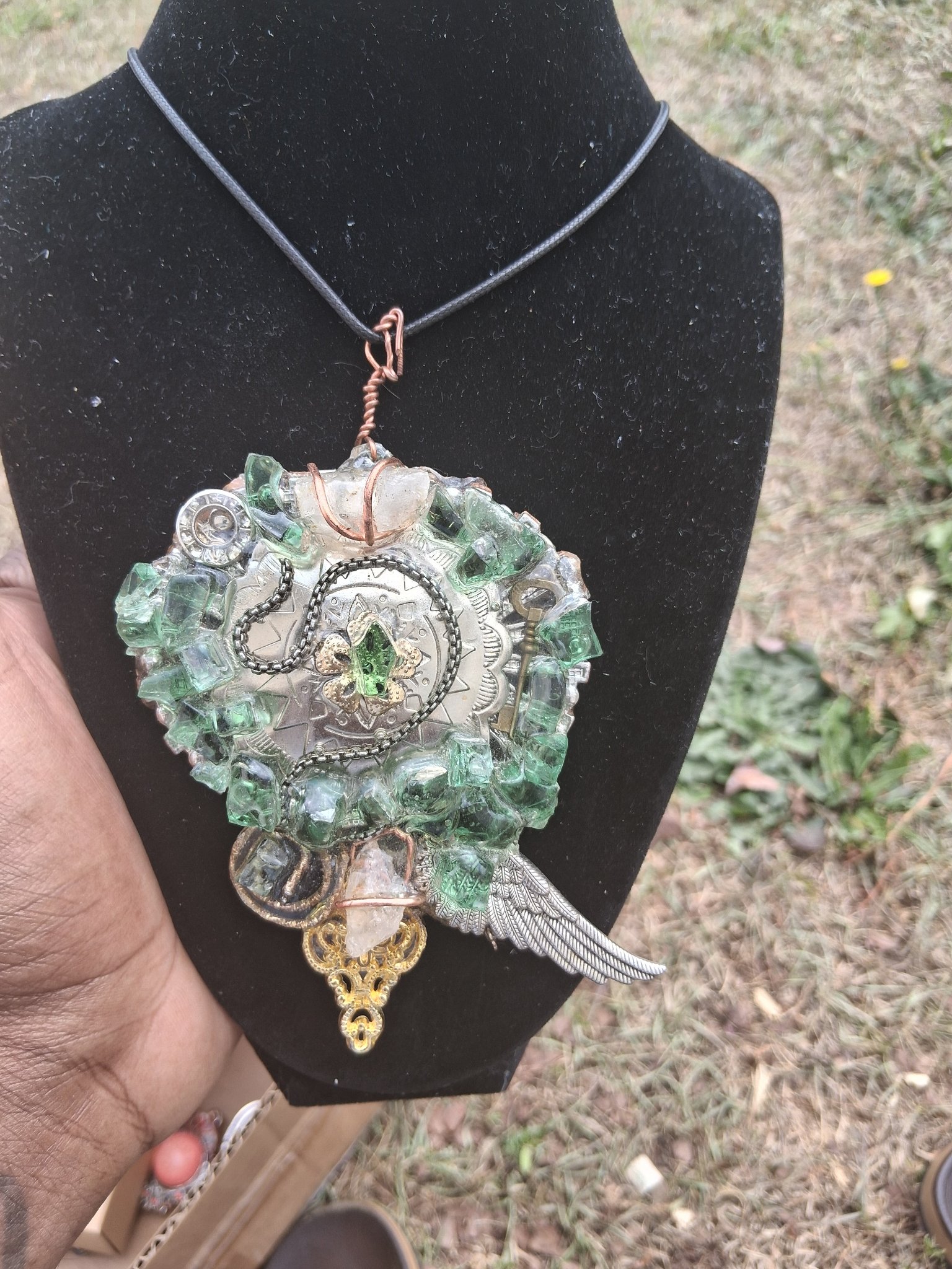 Green and clear crystal pendant with wing and clock details