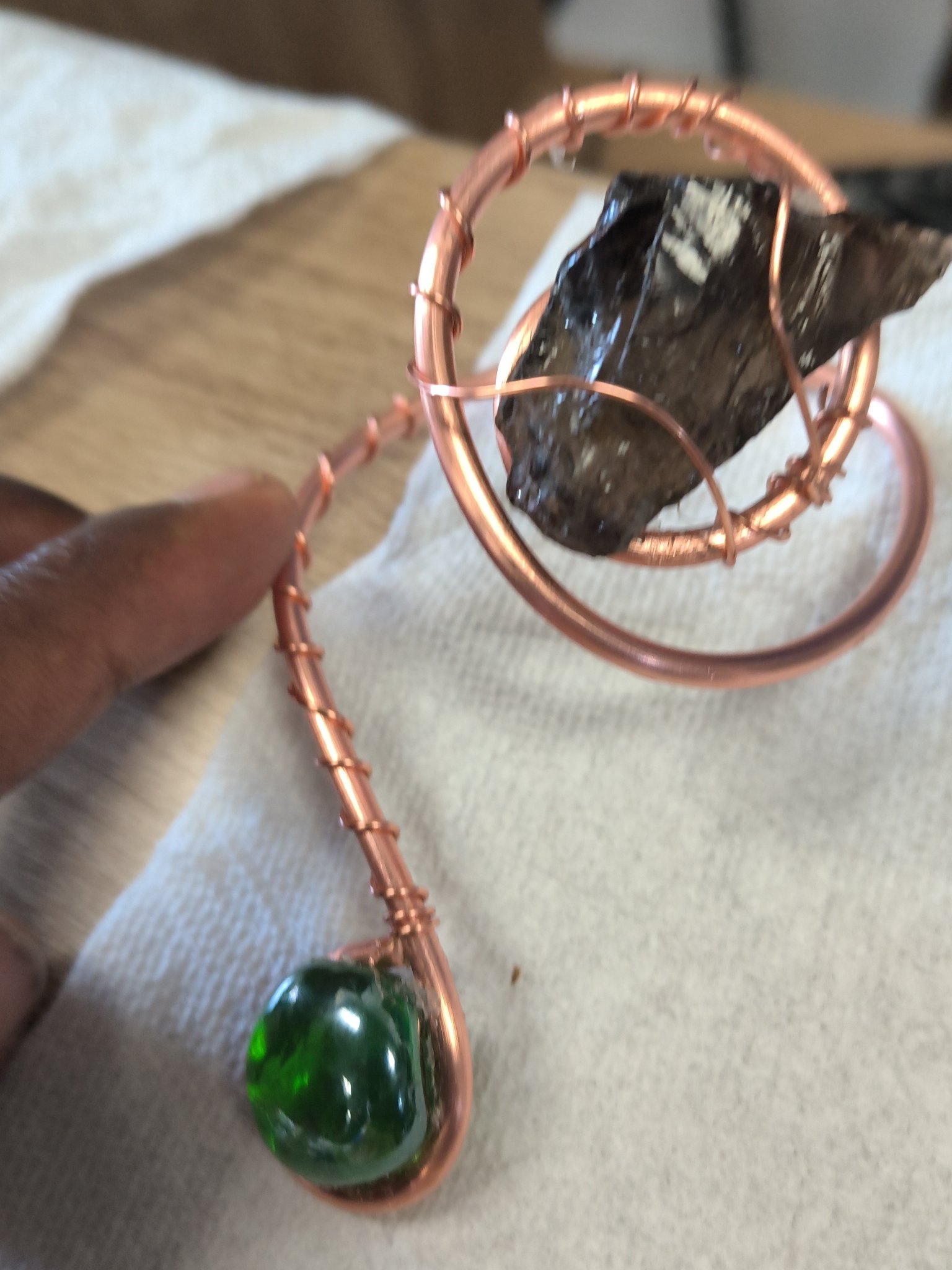 Close view of a copper-wrapped stone with green glass details